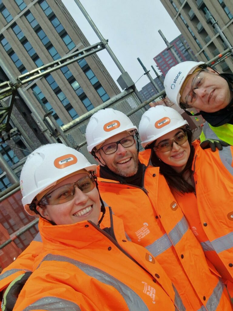 A team of constructors and builders in an orange high vis vests and white helmets. Building student accommodation in East London.