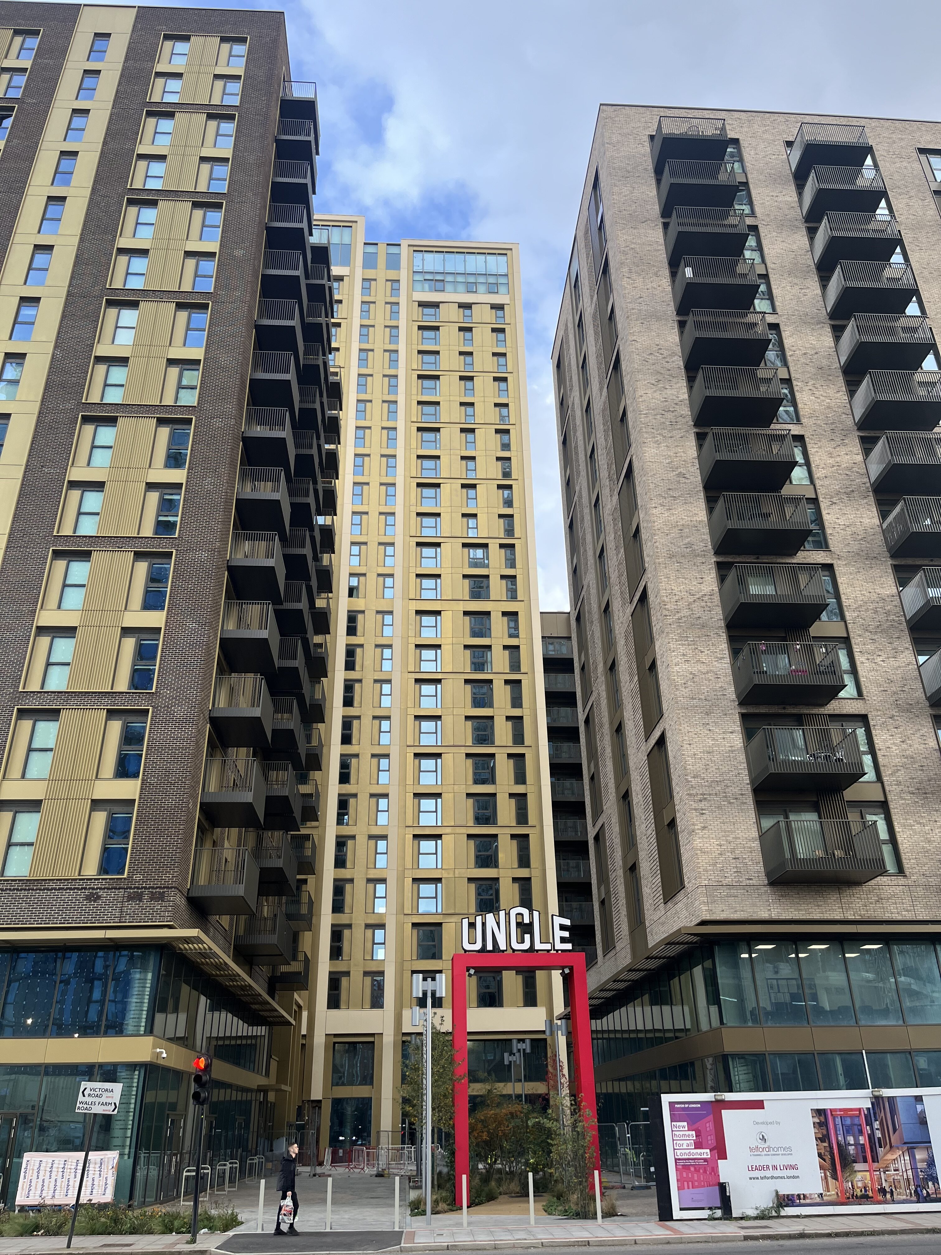 Three tall and large modern buildings with private balconies and windows. Communal space on the ground floor.