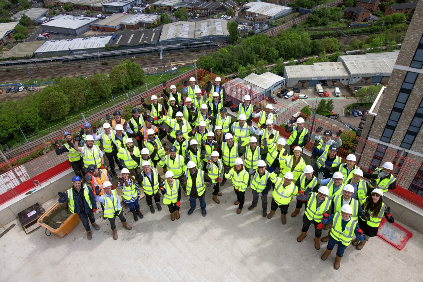 A group of construction site workers celebrating on top of a large building the completion of a perfume factory.
