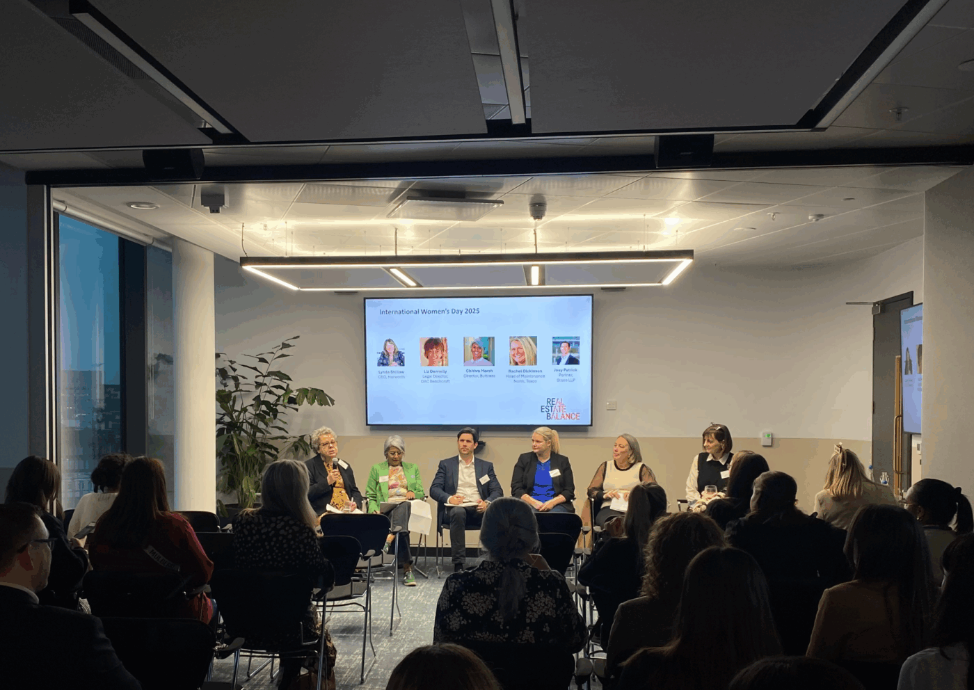 A seminar on international women's day, held in a white room with people watching.