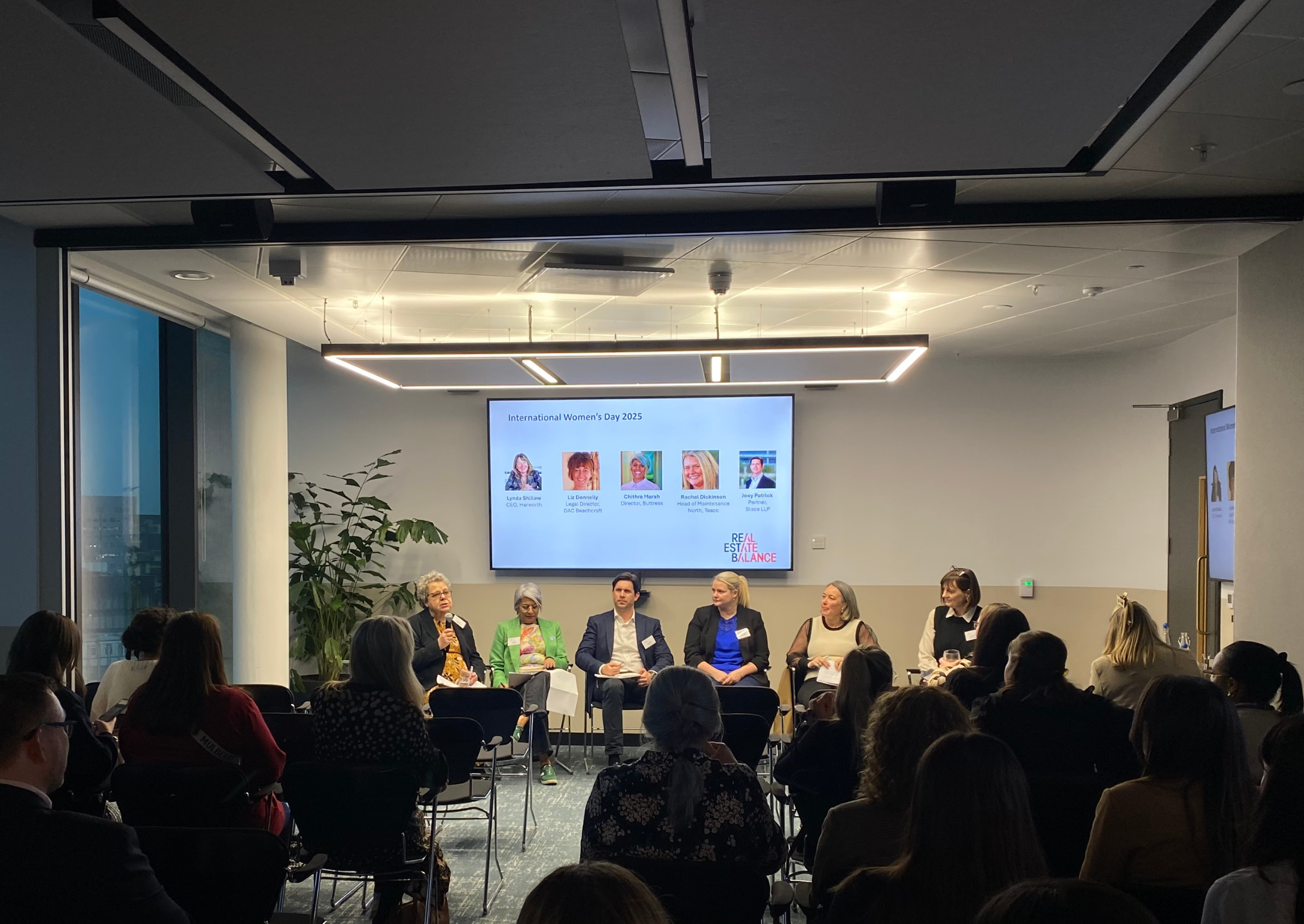 A seminar on international women's day, held in a white room with people watching.
