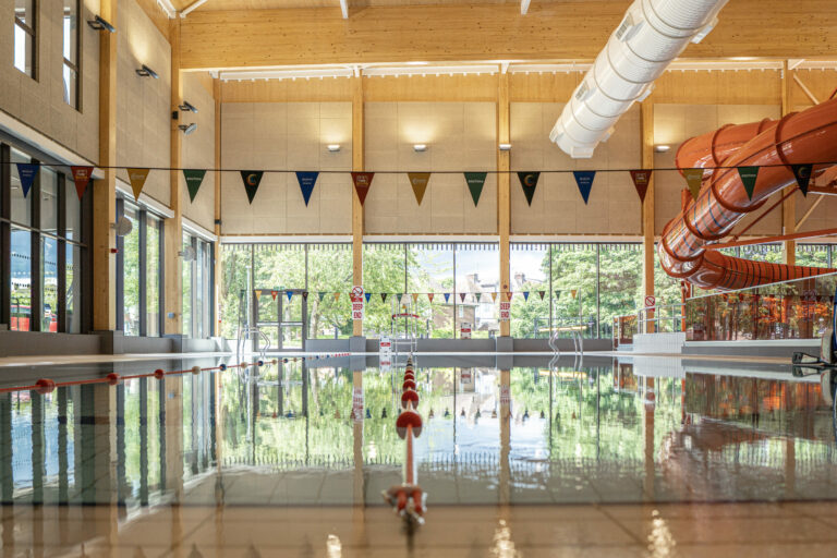 An indoor swimming pool with a calm atmosphere, featuring a red water slide on the right.