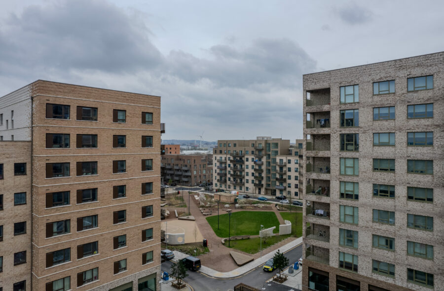 A modern apartment complex with windows and private balconies, situated around a green courtyard.