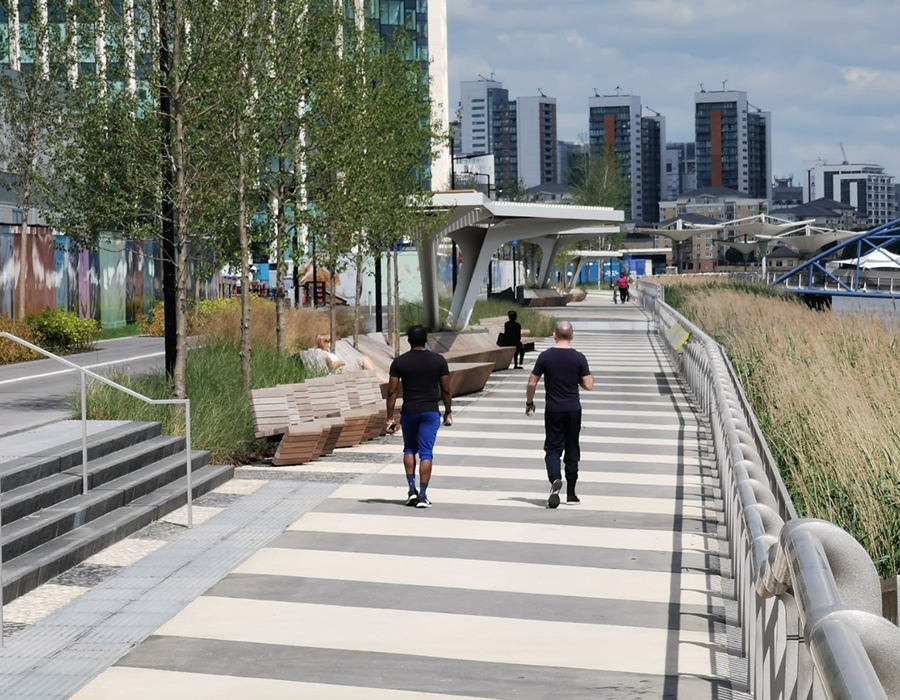 Two people walking along The Tide walkway at Greenwich Peninsula