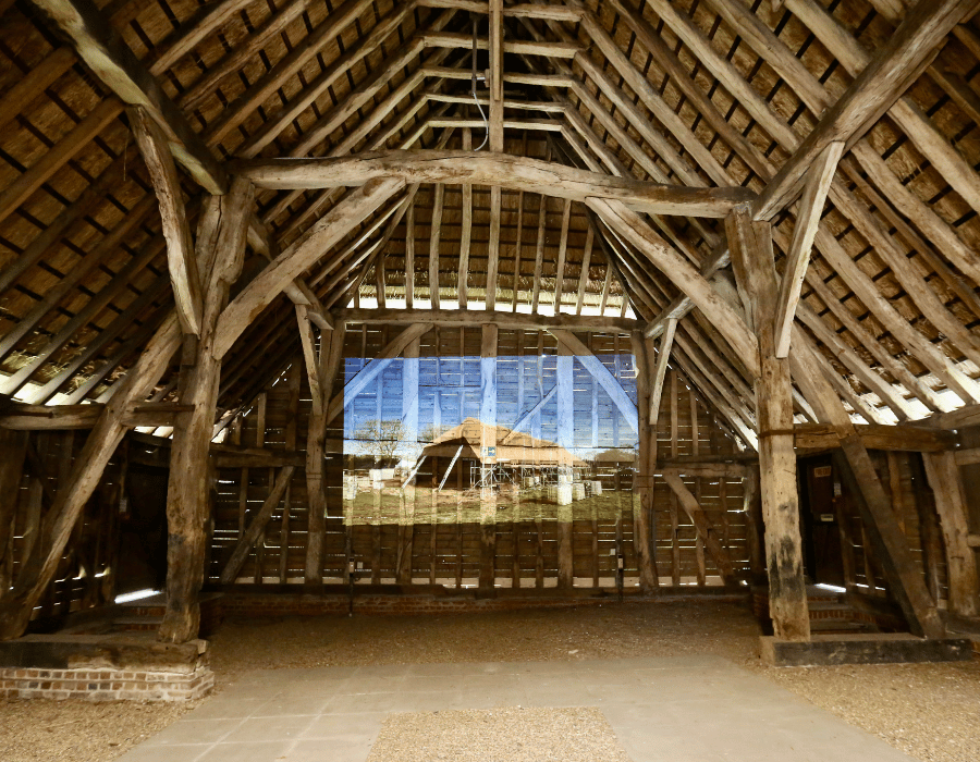 Interior of a large thatched barn with timber panels.