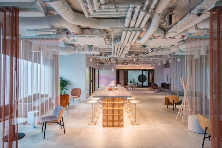 A cozy room featuring a table surrounded by chairs, with a decorative ceiling and curtains. The floor is styled with elegant flooring, and the walls are adorned with tasteful elements that complement the overall interior design.