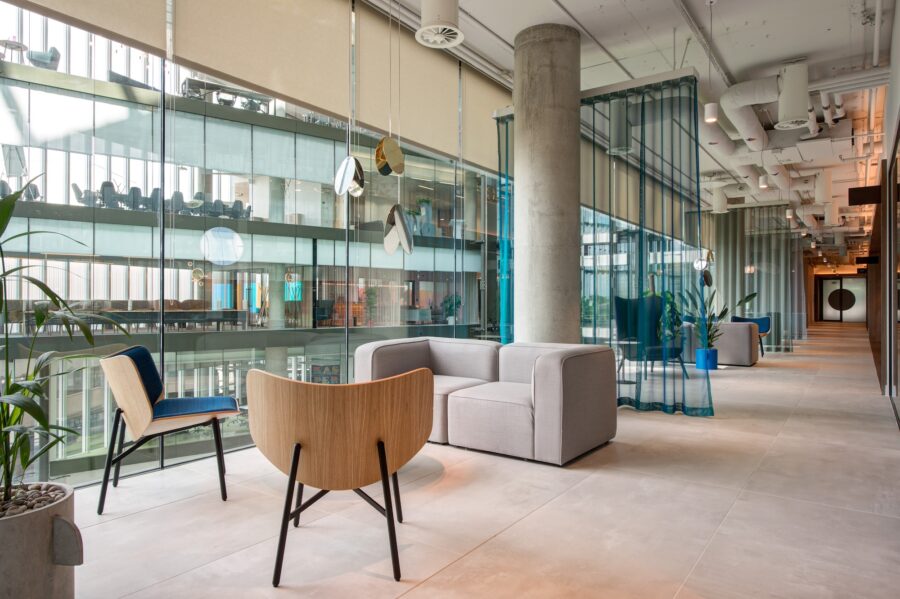 A cozy indoor room featuring a couch and several chairs, with a coffee table in the center. The space is designed for comfort and relaxation, with a window allowing natural light to fill the area.
