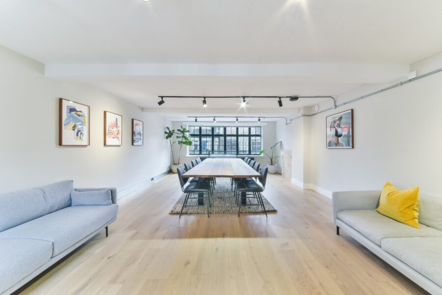 A cozy living room featuring a table surrounded by couches, with a warm and inviting atmosphere. The space includes hardwood flooring and comfortable furnishings, making it ideal for relaxation or social gatherings.