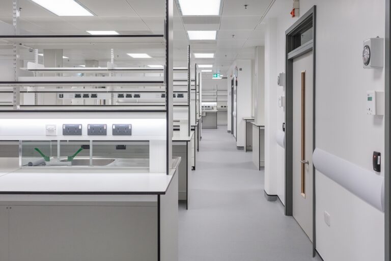 A room featuring white cabinets, with shelves along the walls and a clean floor, designed for an office setting.