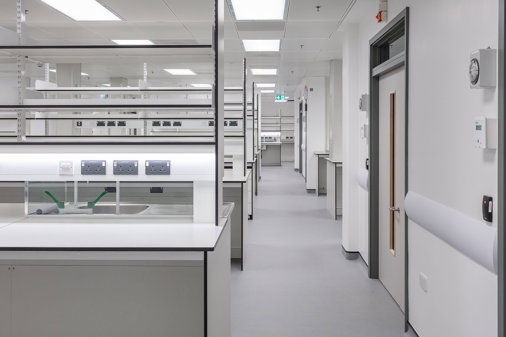 A room featuring white cabinets, with shelves along the walls and a clean floor, designed for an office setting.