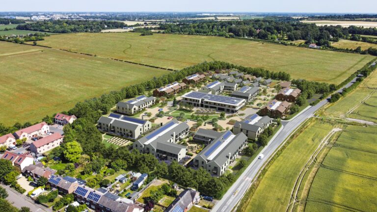 Aerial view of a large group of buildings and roads surrounded by grass and trees, depicting a suburban residential area.