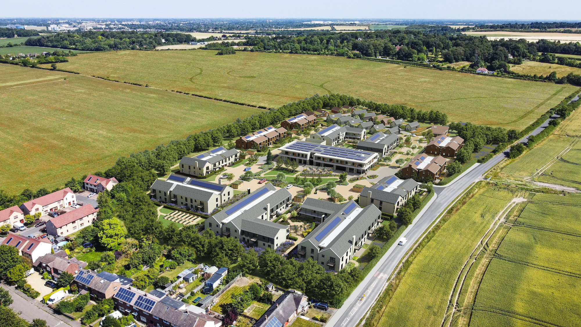 Aerial view of a large group of buildings and roads surrounded by grass and trees, depicting a suburban residential area.