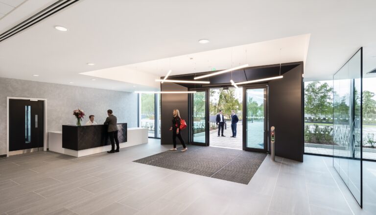 A group of people gathered inside a building lobby, surrounded by artistic decor and interior design elements. The space features walls, flooring, and a ceiling that create an inviting atmosphere.