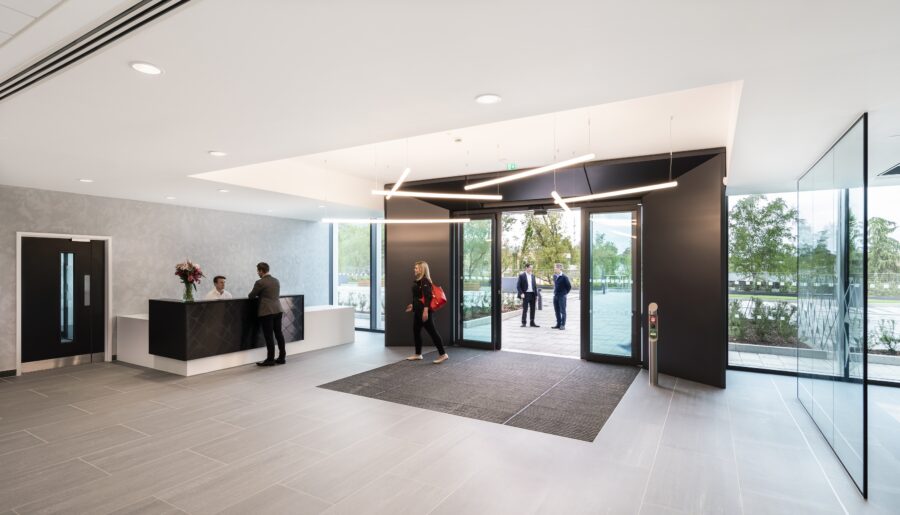 A group of people gathered inside a building lobby, surrounded by artistic decor and interior design elements. The space features walls, flooring, and a ceiling that create an inviting atmosphere.