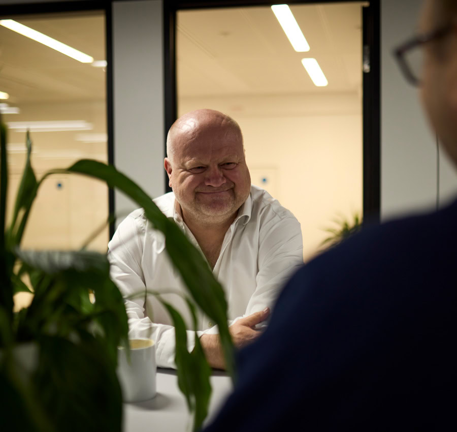 A man wearing a white shirt in a modern office setting with soft lighting.