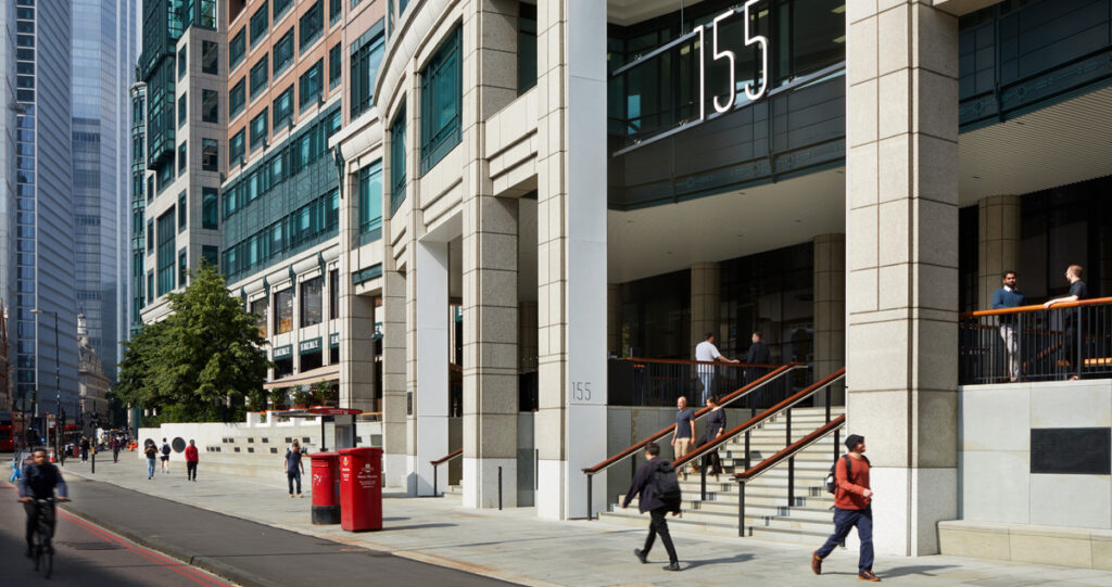 Street view of modern urban architecture with office buildings. People walking past 155 Bishopsgate curved facade along with two red mailboxes are in the foreground.