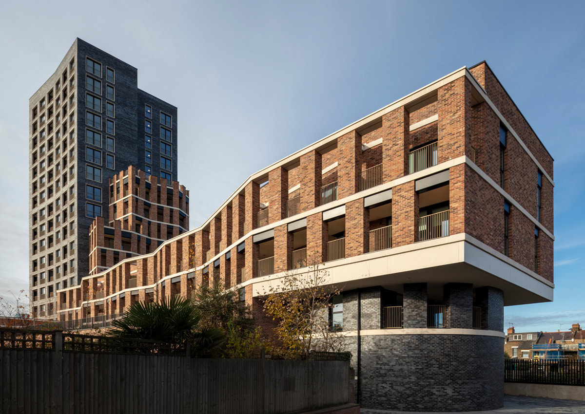 A modern residential building with a brick facade and large windows standing prominently against a clear blue sky, portraying a sense of urban elegance.