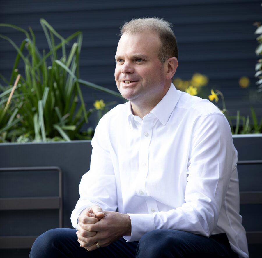 Man in white shirt sitting in a garden with daffodils in the background