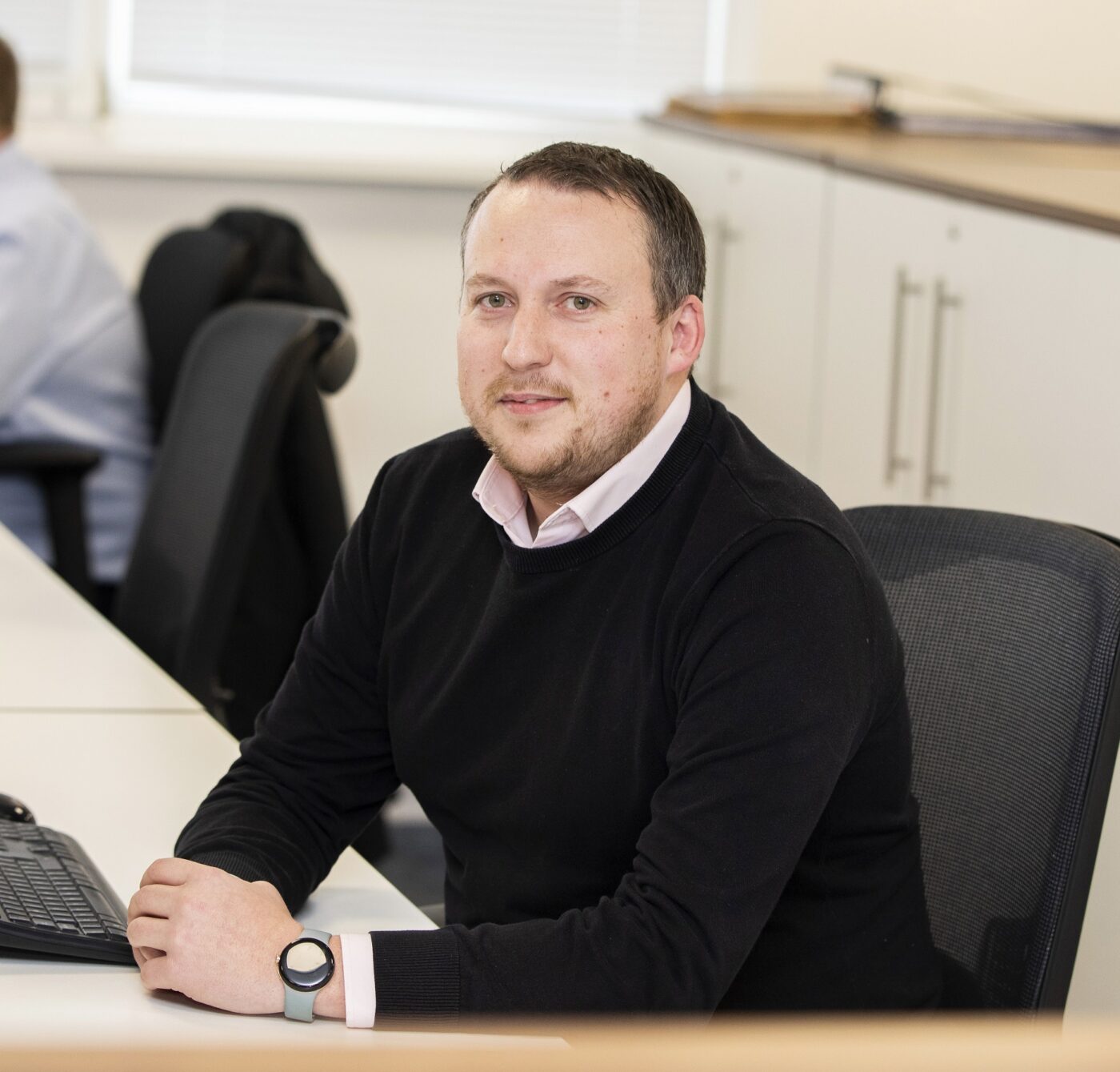 Man in black jumper sitting at computer desk