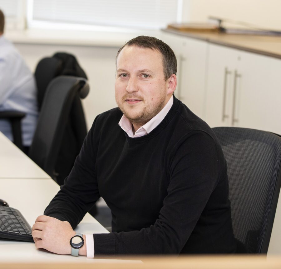 Man in black jumper sitting at computer desk