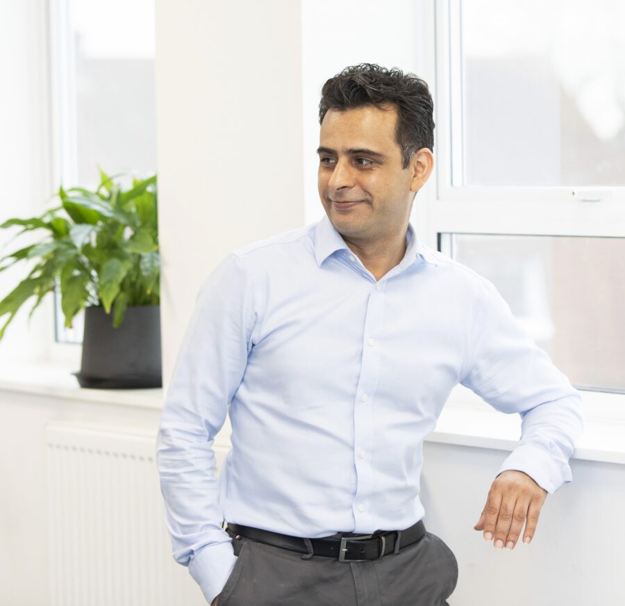 Man in blue shirt leaning on a windowsill with a plant in the background