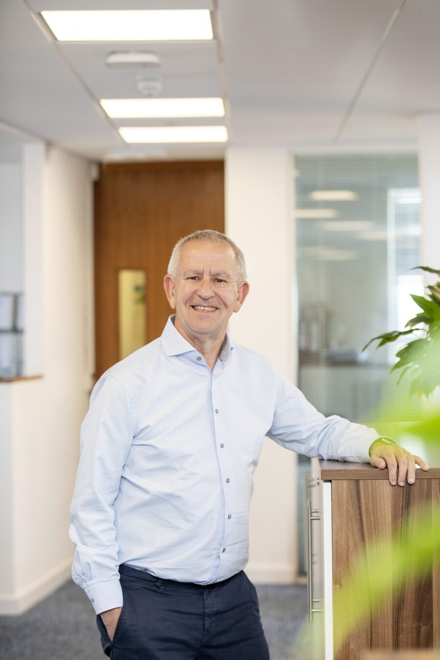 Man standing in office with arm resting on cabinet