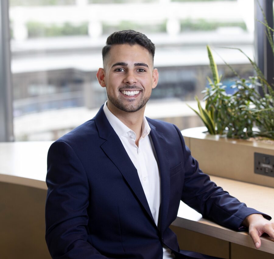 Man in suit sitting in breakout space smiling at the camera