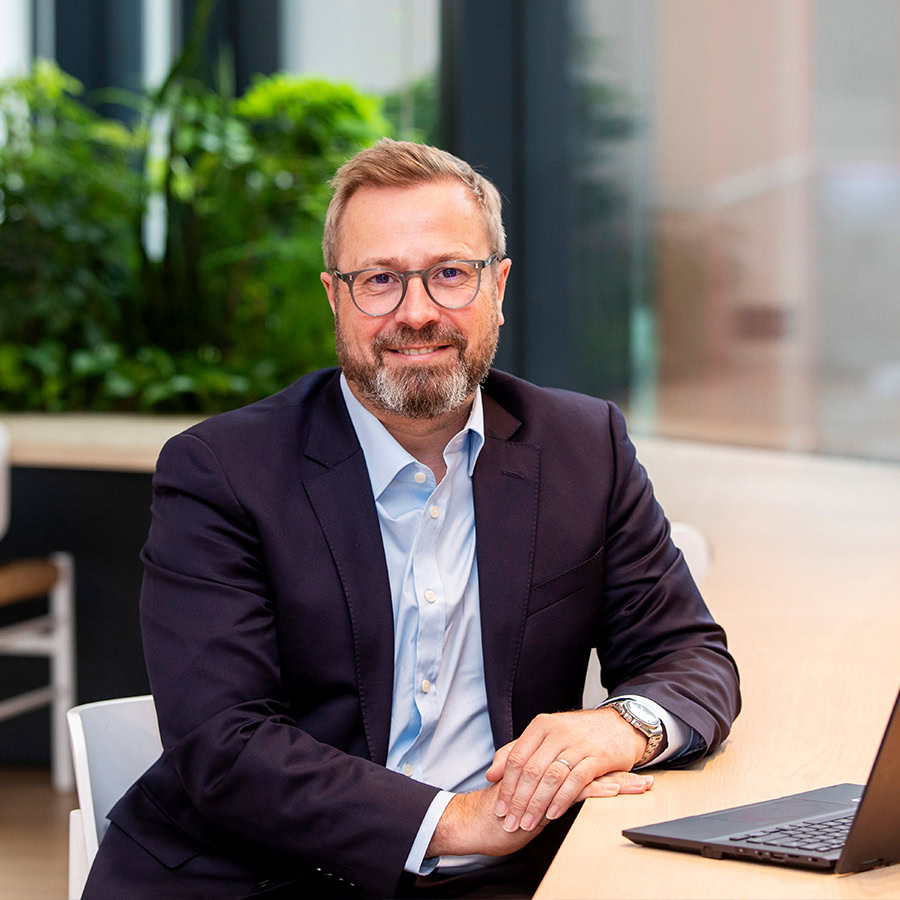 Man smiling at desk with a laptop in front of him.