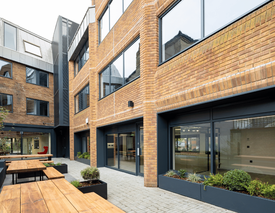 Exterior view of an office building with a bench-lined seating area in front.
