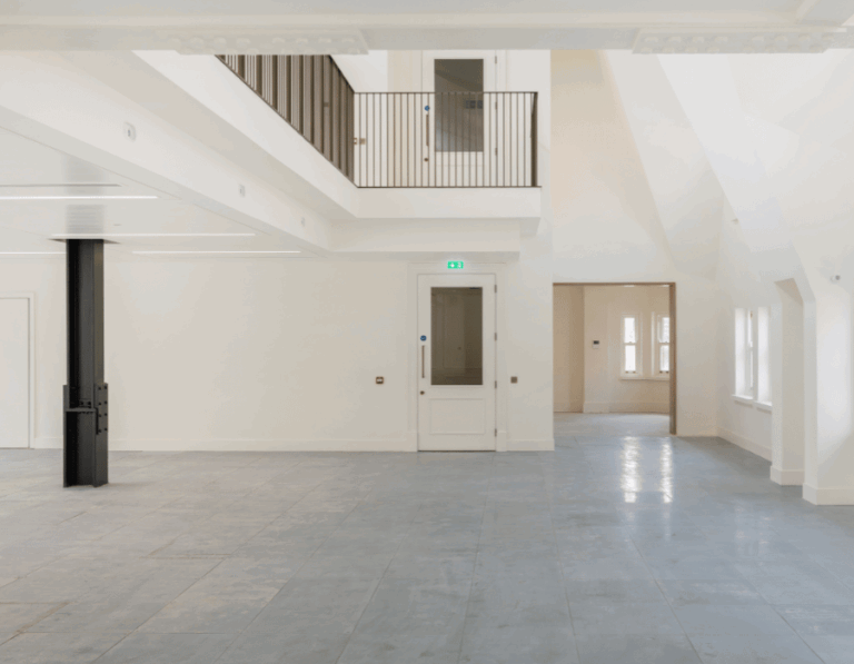 Spacious, empty interior with white walls, large windows, and tiled floor.