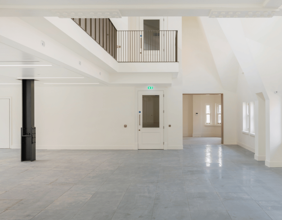 Spacious, empty interior with white walls, large windows, and tiled floor.