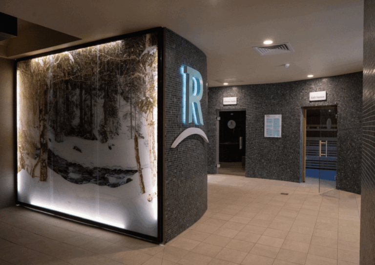 Modern indoor spa area with tiled walls, and doors leading to sauna and pool facilities.
