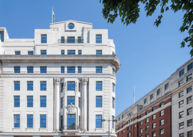 Historic white stone building with tall windows and decorative columns under a clear blue sky.
